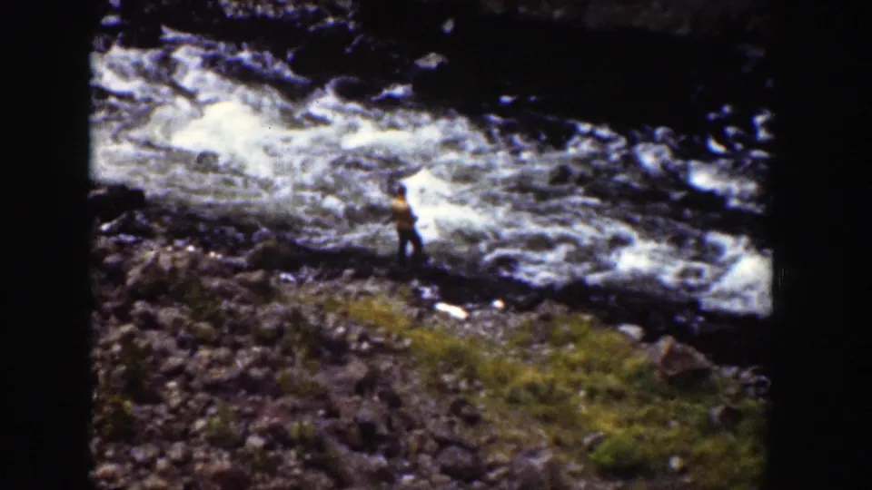 1939 Wyoming 8mm frame showing a lone figure by a turbulent river downstream from the waterfall.