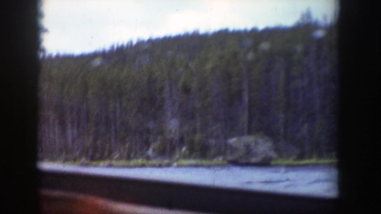 1939 Wyoming home-movie view of a river and evergreen hillside passing outside a dark vehicle window.