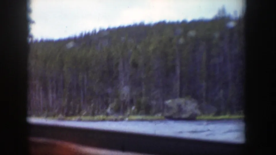 1939 Wyoming home-movie view of a river and evergreen hillside passing outside a dark vehicle window.