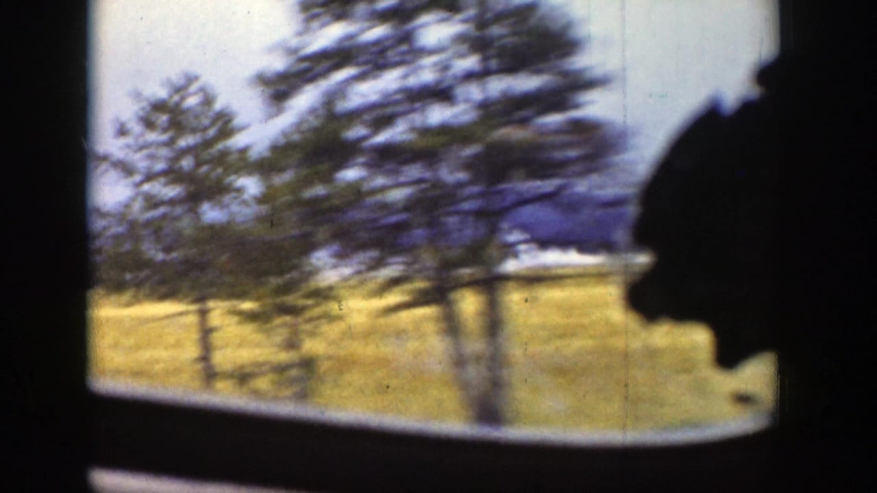 1939 Wyoming 8mm view from inside a moving train, with blurred trees, golden fields, and distant mountains beyond the window.