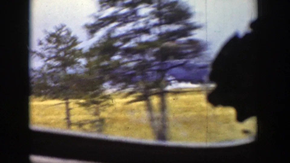 1939 Wyoming 8mm view from inside a moving train, with blurred trees, golden fields, and distant mountains beyond the window.