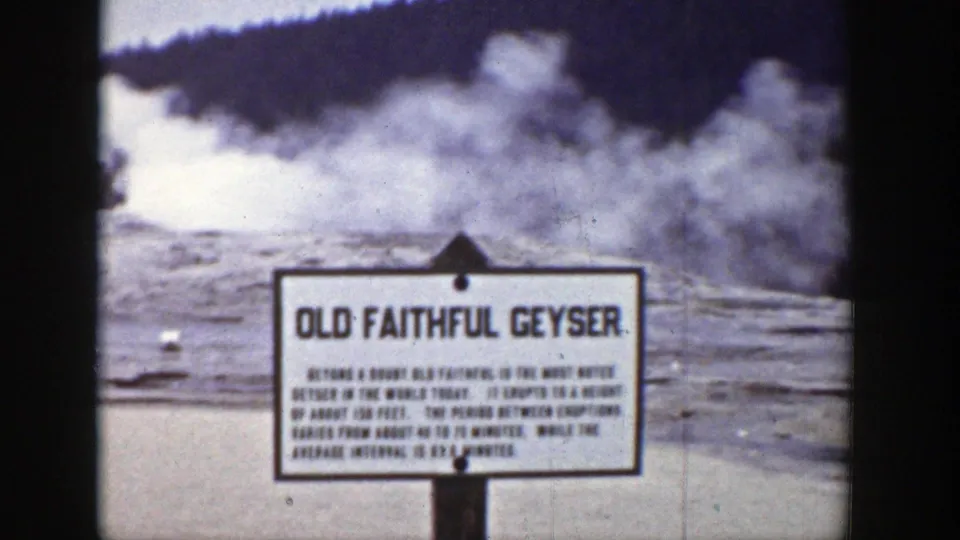 1939 Wyoming view of the Old Faithful Geyser sign with a pale steam plume rising behind it in Yellowstone.