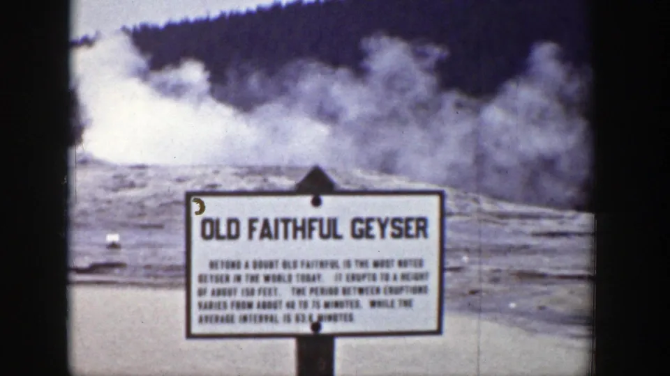 The Old Faithful Geyser sign remains centered as steam spreads across the Yellowstone basin behind it.