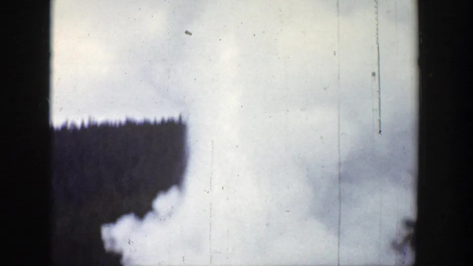 1939 Wyoming 8mm frame where the geyser steam expands across the view, partly obscuring the forest.