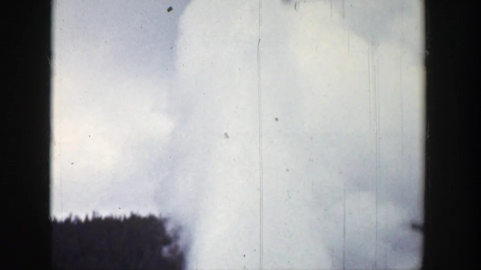 1939 Wyoming 8mm frame showing white-gray smoke rising beyond a dark forest edge under a pale sky.