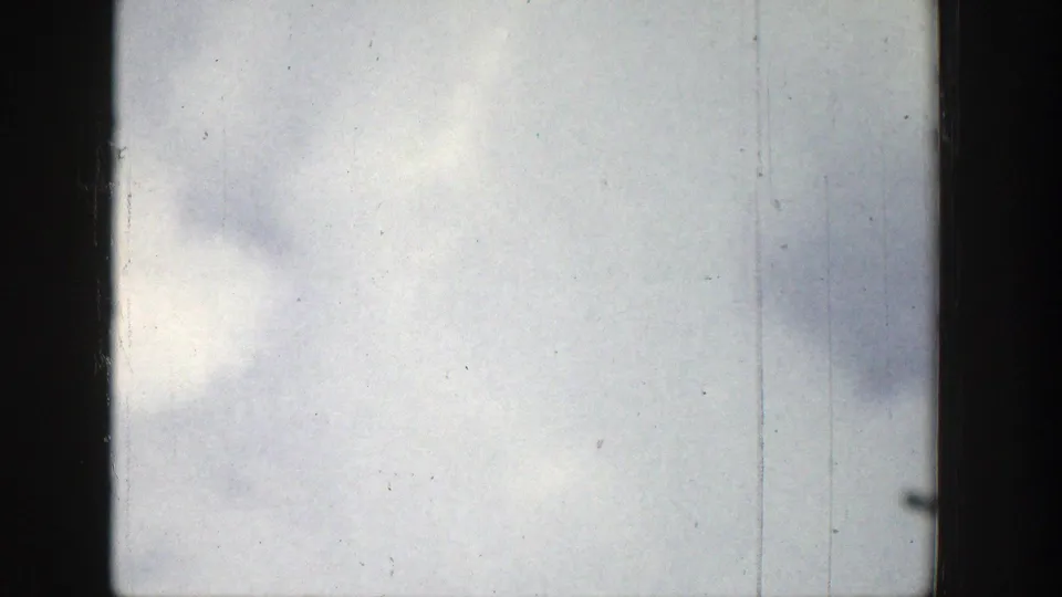1939 Wyoming 8mm frame showing an overcast sky through a dark window edge, with dust, grain, and vertical scratches.