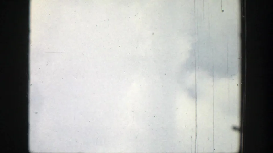 Clouded sky in a 1939 Wyoming home-movie frame, divided by dark window structure and marked by film dust and scratches.