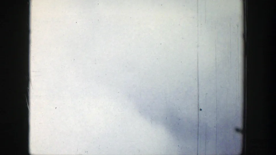 1939 Wyoming 8mm view of soft gray clouds through window framing, showing a horizontal divider, grain, dust, and scratches.