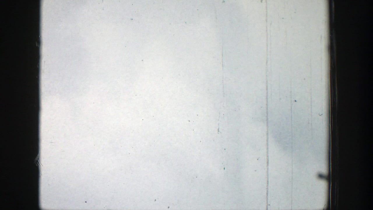 Overexposed pale sky framed by dark 8mm film edges and visible scratches.