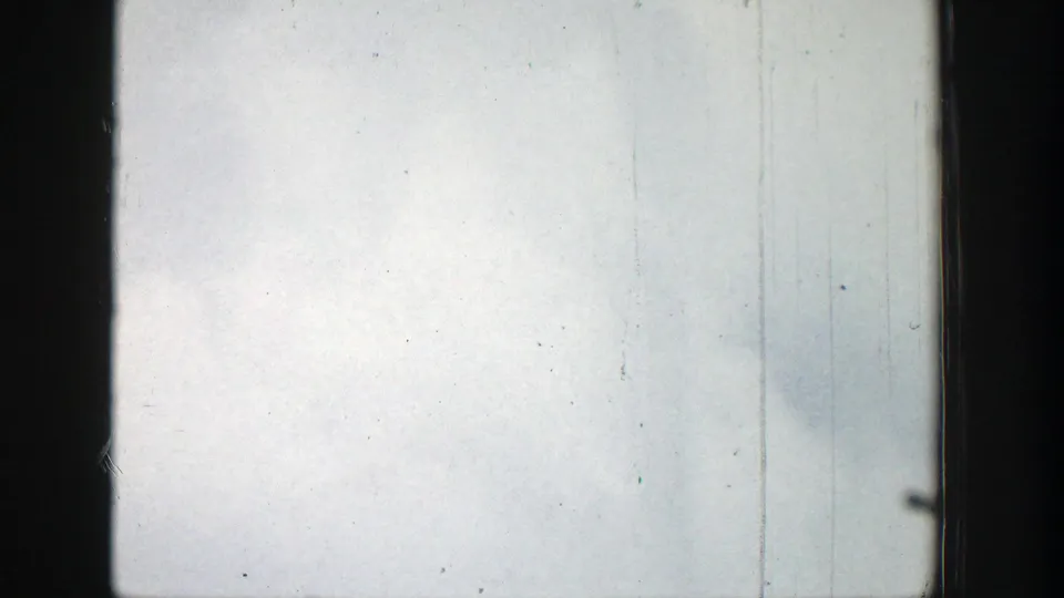 Overexposed 1939 8mm Wyoming frame with pale sky, dark gate edges, scratches, and dust, before the geyser is clearly visible.