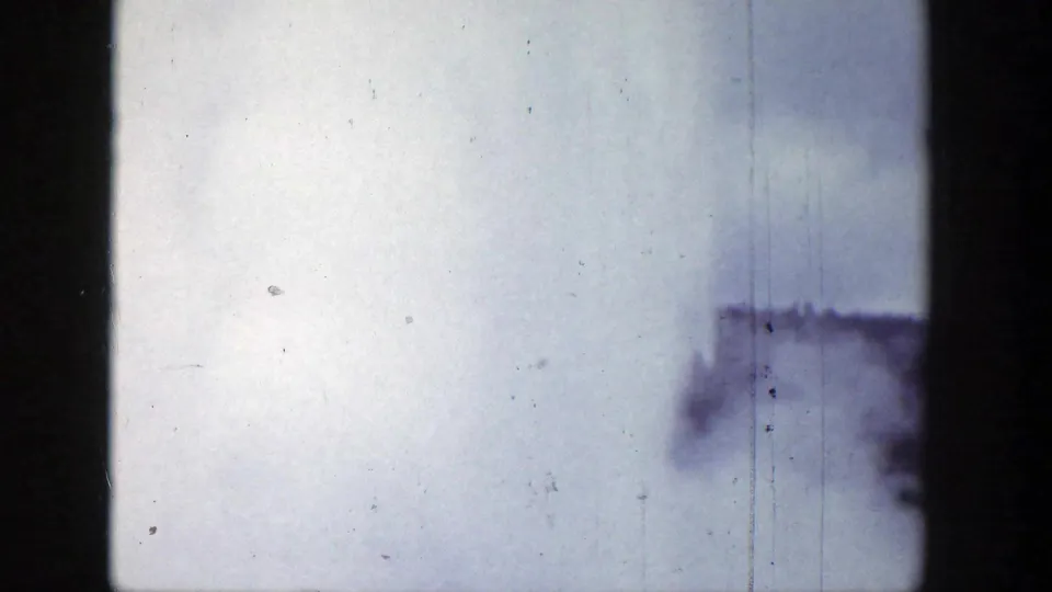 A small geyser steam or water plume appears at the lower right of the 1939 Wyoming 8mm frame under a pale, scratched sky.