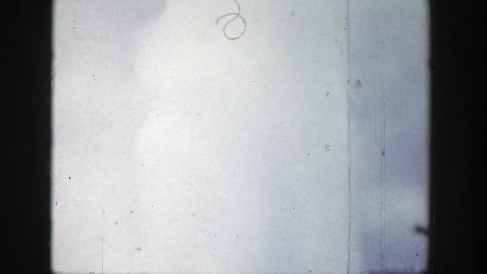 1939 Wyoming 8mm frame showing a pale sky and soft geyser vapor rising near the lower edge, with film scratches and dark frame borders.