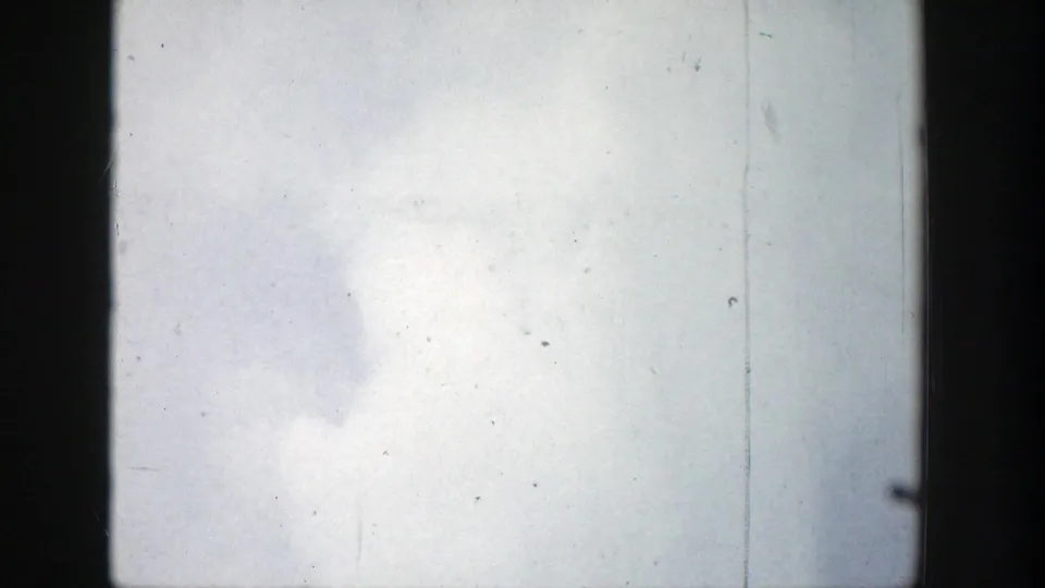 1939 Wyoming 8mm frame with a bright geyser steam cloud swelling upward against the sky, marked by dust and vertical film wear.