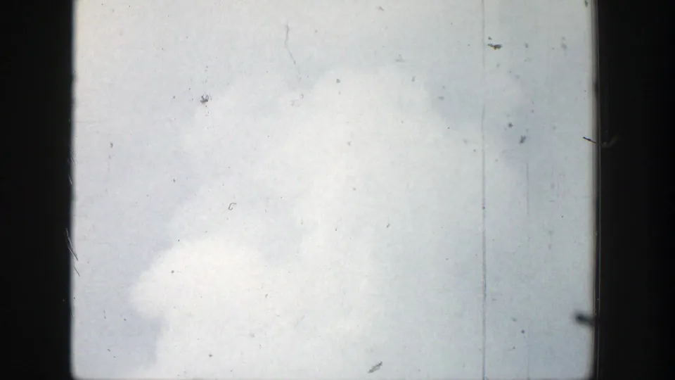 1939 Wyoming 8mm frame showing low geyser vapor at the bottom edge beneath a pale, washed sky with visible film grain and scratches.