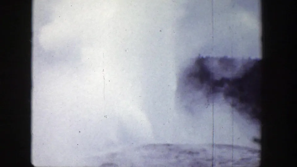1939 Wyoming 8mm frame showing darker geyser spray and white vapor rising from the lower right, with frame borders and aged film texture.