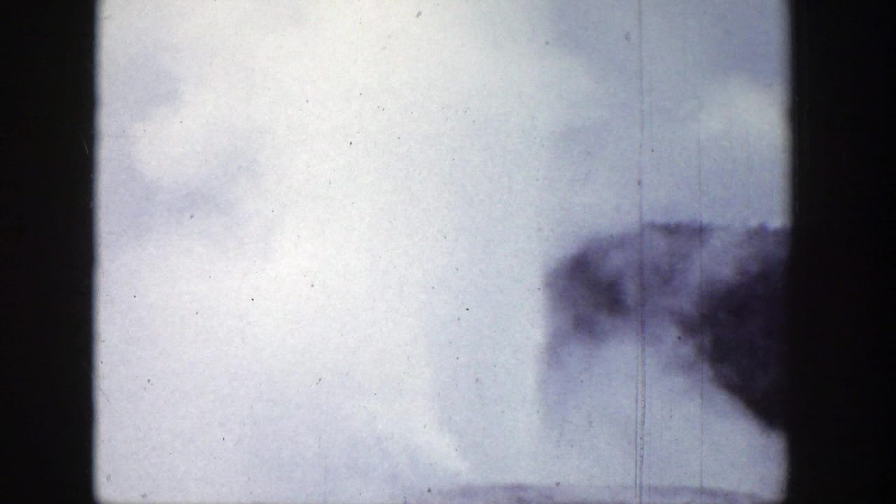 Steam plume rising beyond dark film-frame edges under a pale sky.