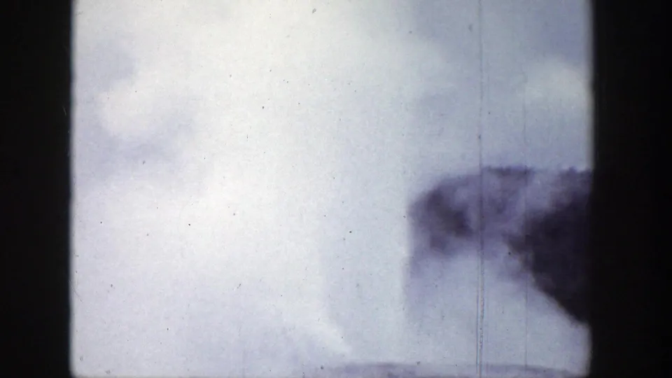1939 Wyoming 8mm frame showing a geyser steam plume rising against a pale sky, with dark gate edges and visible film wear.