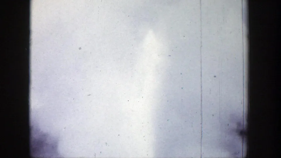 1939 Wyoming 8mm frame with a tall geyser plume and misty spray filling the right side of a bright sky.