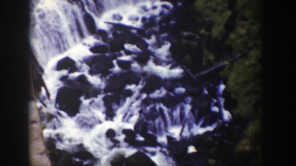 1939 Wyoming home-movie frame of a rocky waterfall partially obscured by a dark vertical foreground shape.