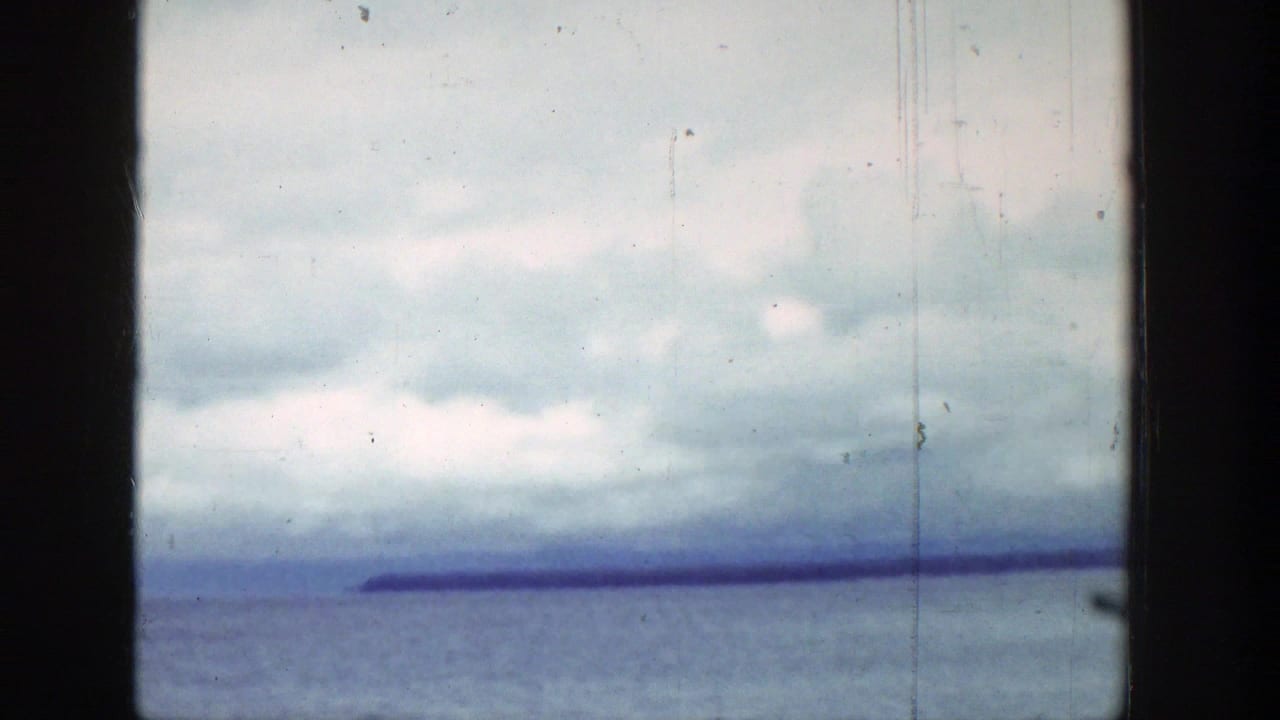 1939 Wyoming 8mm view of a lake under layered clouds, with a distant shoreline visible through vehicle-like framing.