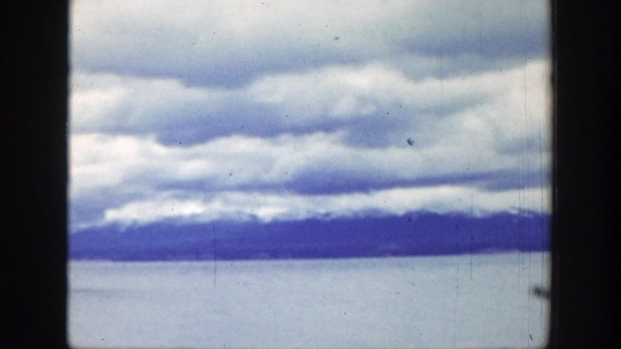 Cloud bands over water with distant mountains on the horizon.