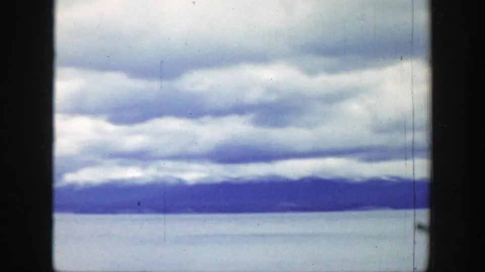 Wide 1939 home-movie view of layered clouds over water with a low mountain horizon in Wyoming.