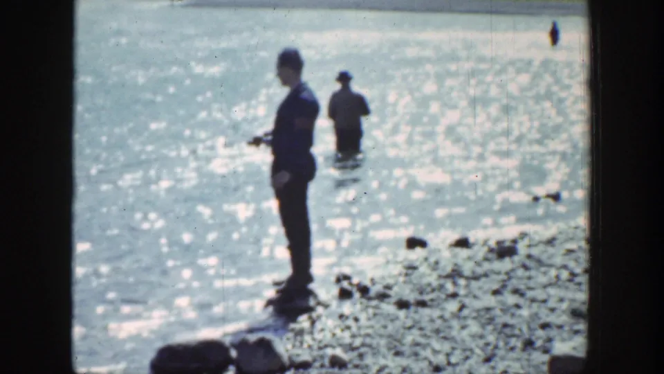The 1939 Wyoming home movie shows a man with fishing gear on a rocky shore while another figure stands in shallow water.