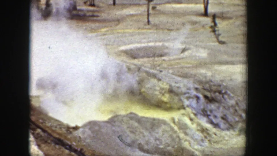 Close 1939 Wyoming home-movie view of a steaming yellow geothermal pool bordered by pale mineral deposits and rough rock.