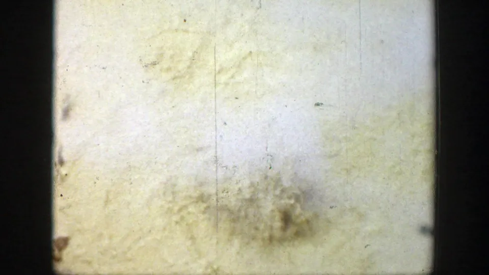 Deteriorated 8mm film stock from the Wyoming 1939 metadata, showing pale yellowing, edge shadow, vertical scratches, stains, and mold-like residue.