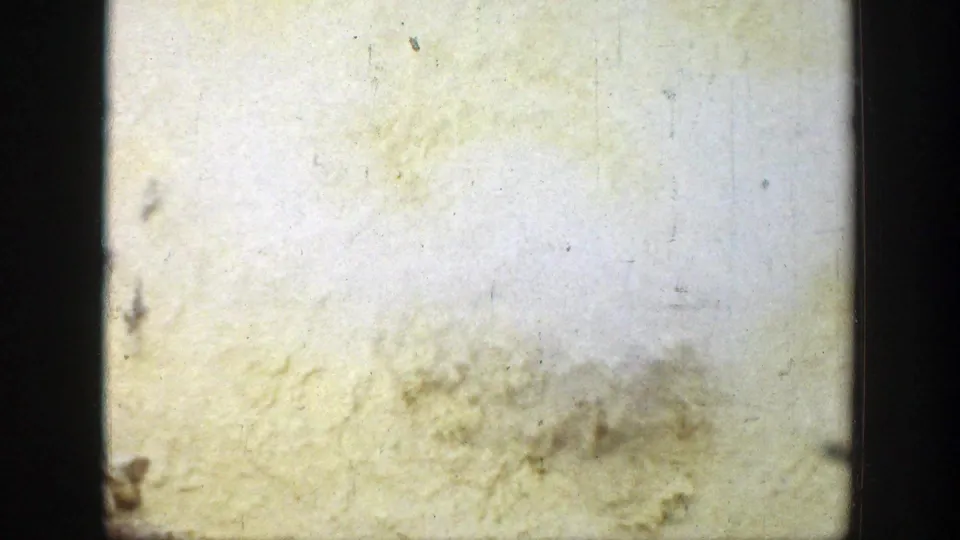 A faded 8mm frame with heavy pale exposure, film scratches, dark borders, and minimal visible Wyoming scene detail.
