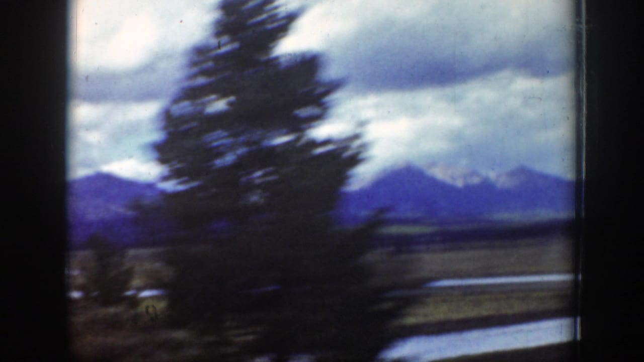 Blurred tree and mountain landscape seen through a train window.