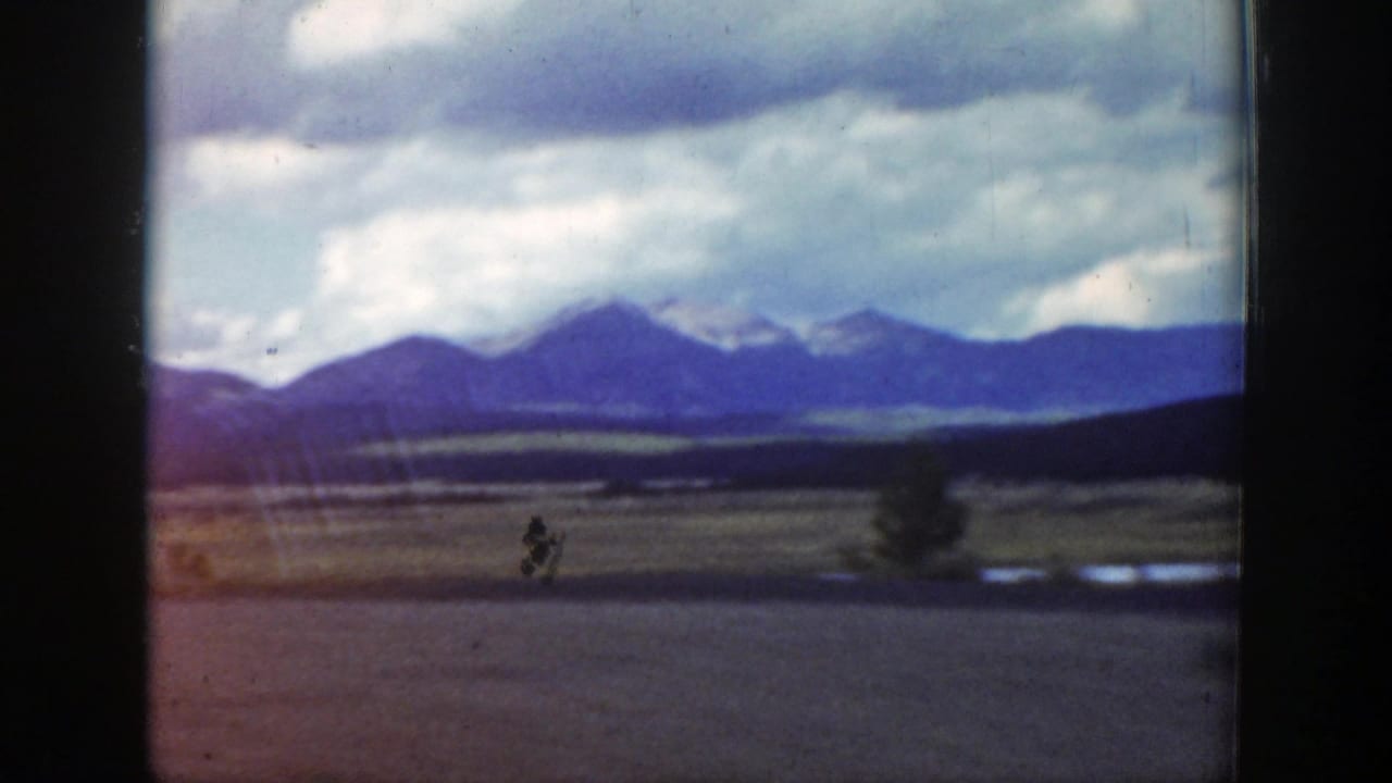 Open countryside with distant mountains and a small car on a road.