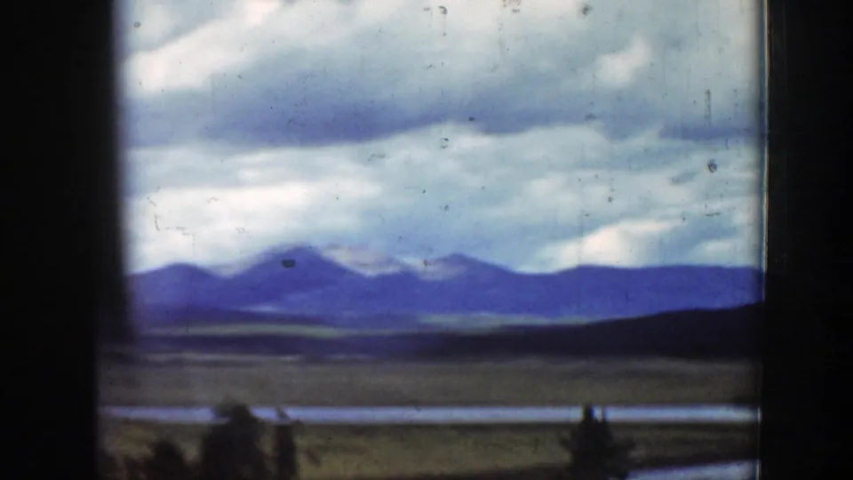 1939 Wyoming landscape from a train window, with blue mountain ridges, cloudy sky, open plain, and dark vertical window edges.