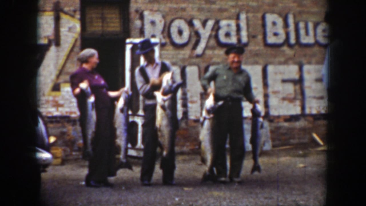 A woman and two men hold large fish while standing near a doorway and painted wall sign.