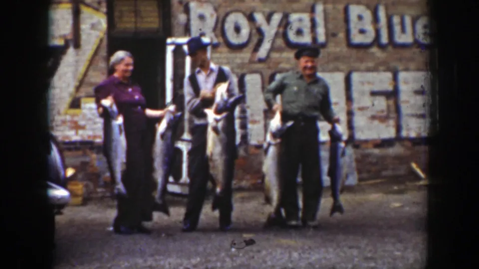 The 1939 Wyoming fishing scene shows the adults holding several sizable fish, with soft 8mm color and a faded wall sign in the background.
