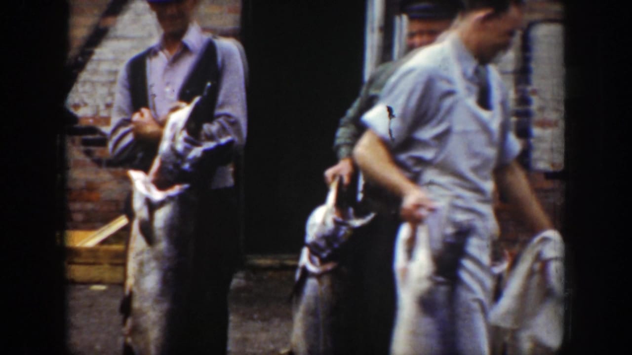 Men carrying large fish move past a brick storefront doorway.