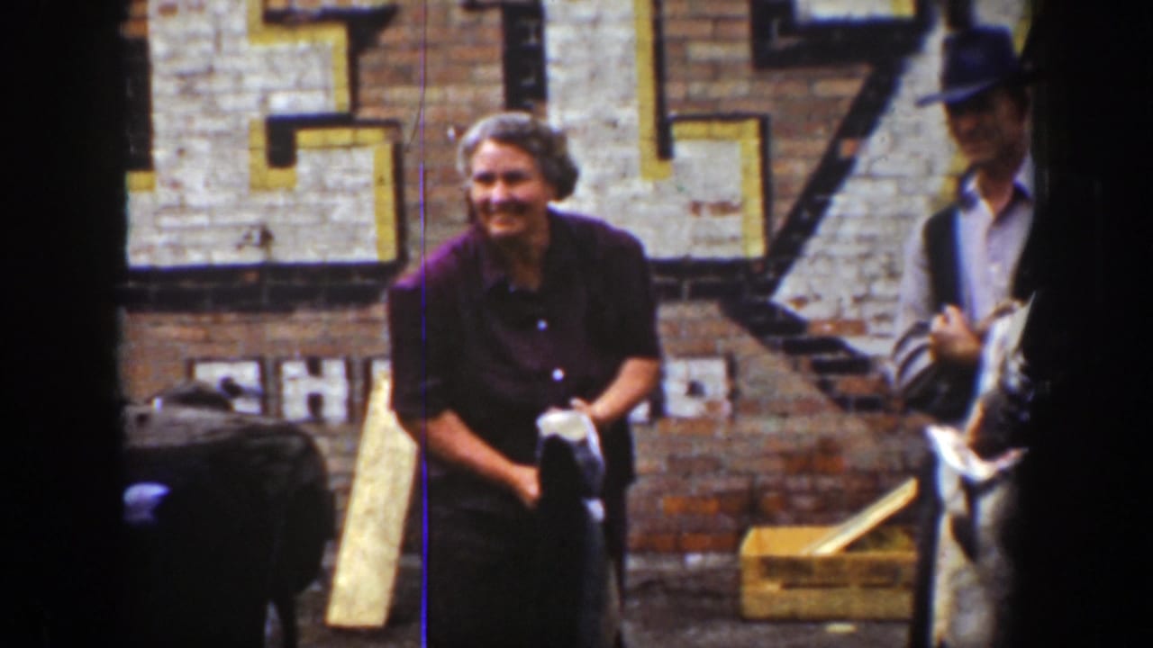 Adults stand outside a brick building while a smiling woman holds a fish.