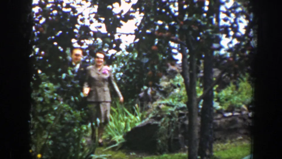 In 1939 Wyoming home-movie footage, a suited couple walks toward the camera through fruit trees and garden greenery.