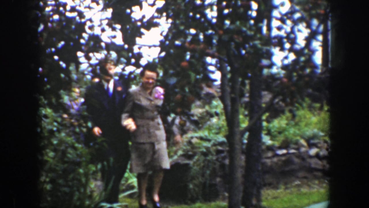 Couple standing close together among garden trees and greenery.