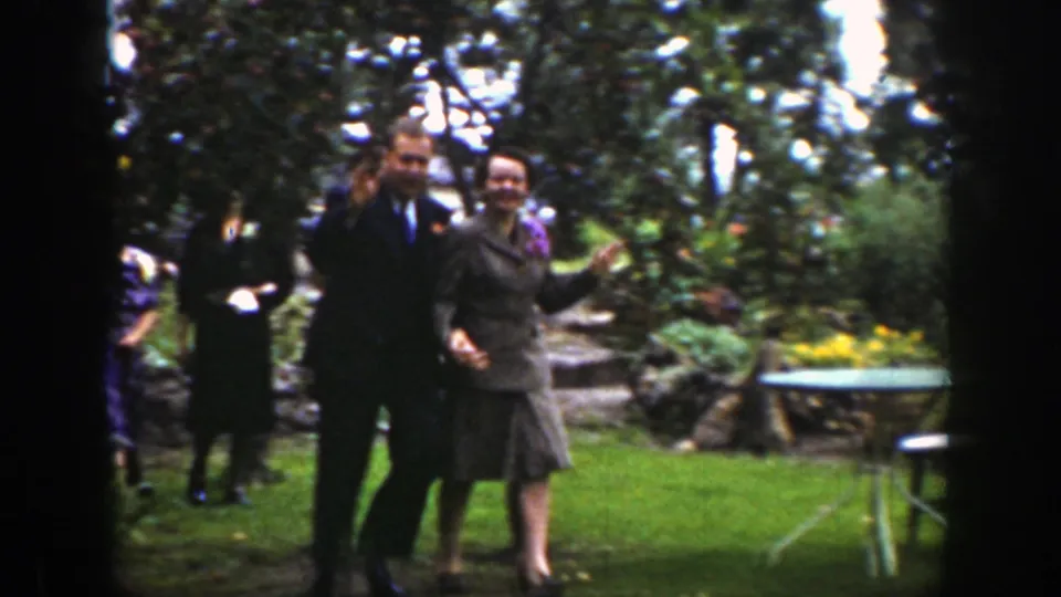 In 1939 Wyoming home-movie footage, a smiling couple holds hands while other adults walk behind them in a leafy garden.