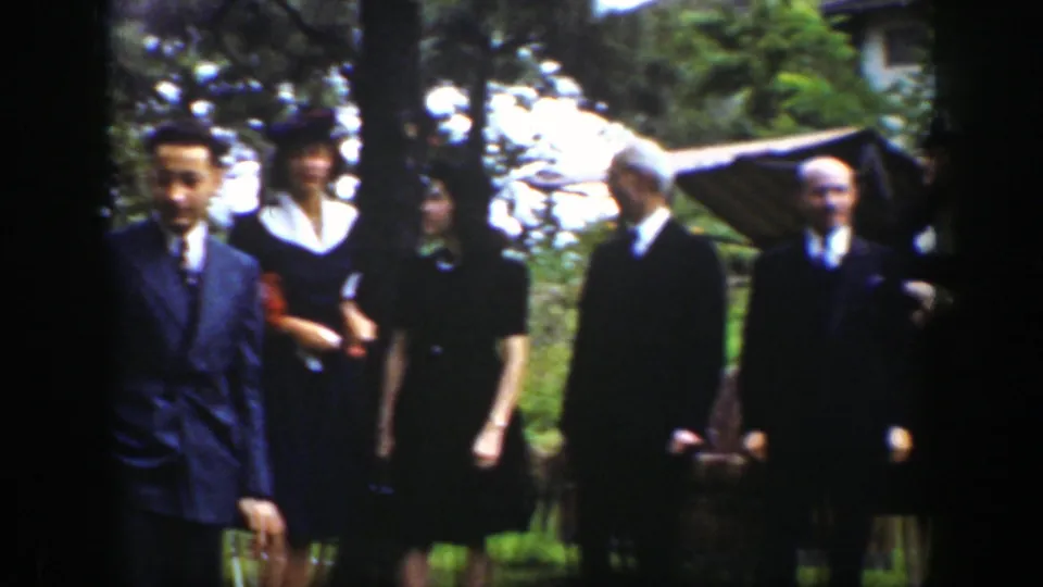 Formally dressed adults stand in a Wyoming garden in 1939, with a striped canopy and trees visible behind them.