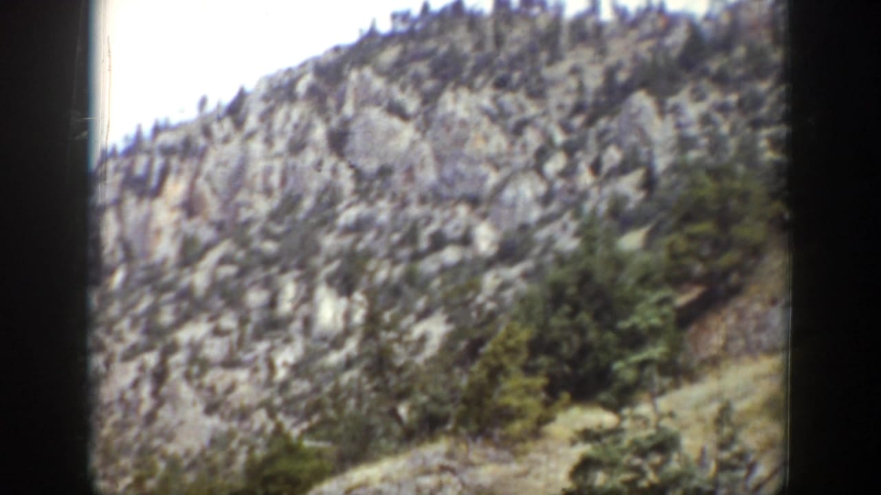 1939 Wyoming 8mm frame showing a rugged, tree-dotted mountainside beneath an overcast sky.