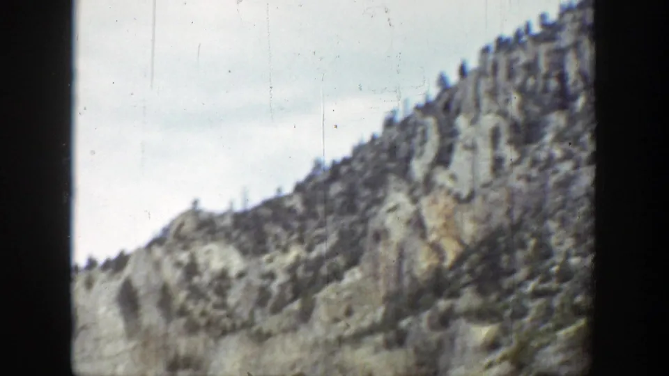 1939 Wyoming 8mm frame of a sloping mountain face, its rocky surface broken by small evergreen trees.