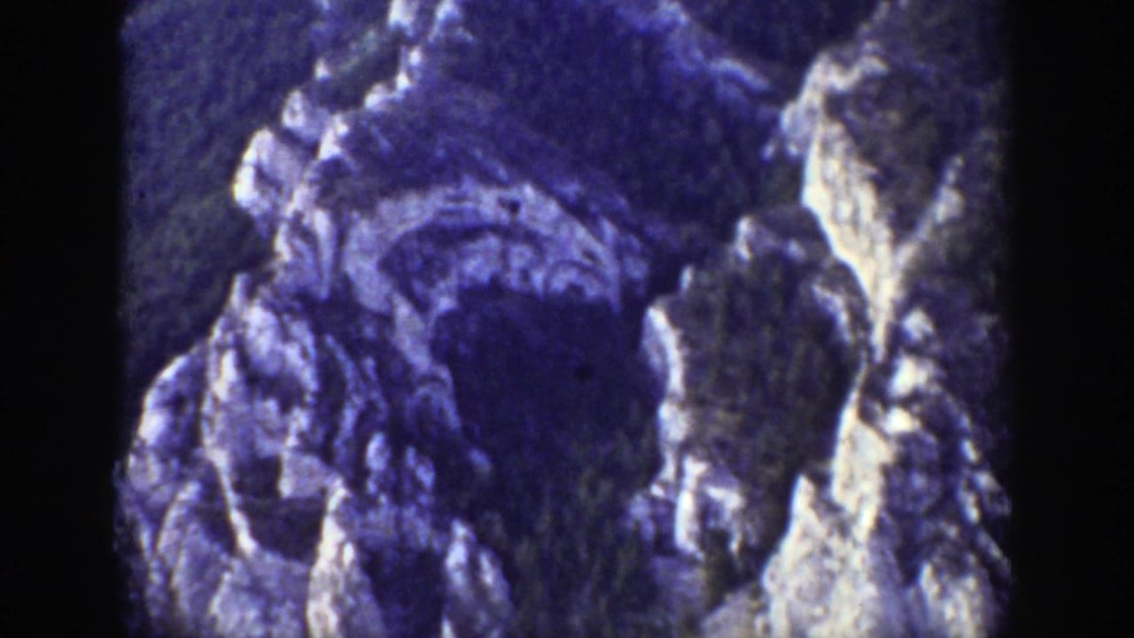 Close view of pale rock cliffs and dark evergreen-covered slopes.