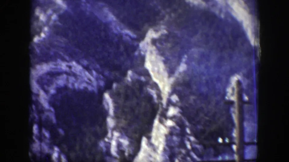 1939 Wyoming 8mm frame showing a rocky mountain slope, dark valley terrain, and a utility pole near the rail route.