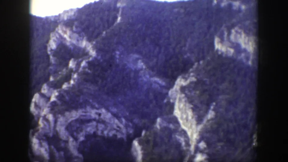 1939 Wyoming 8mm frame showing rugged gray cliffs and wooded slopes, with soft focus and dark film edges.