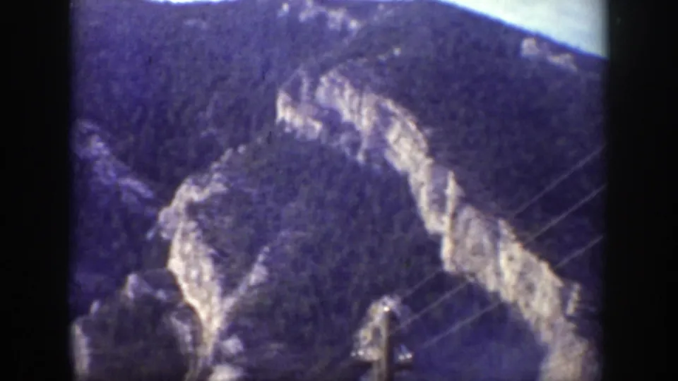 Wyoming mountain terrain from 1939 home-movie footage, with thin utility wires cutting across the rocky slope.
