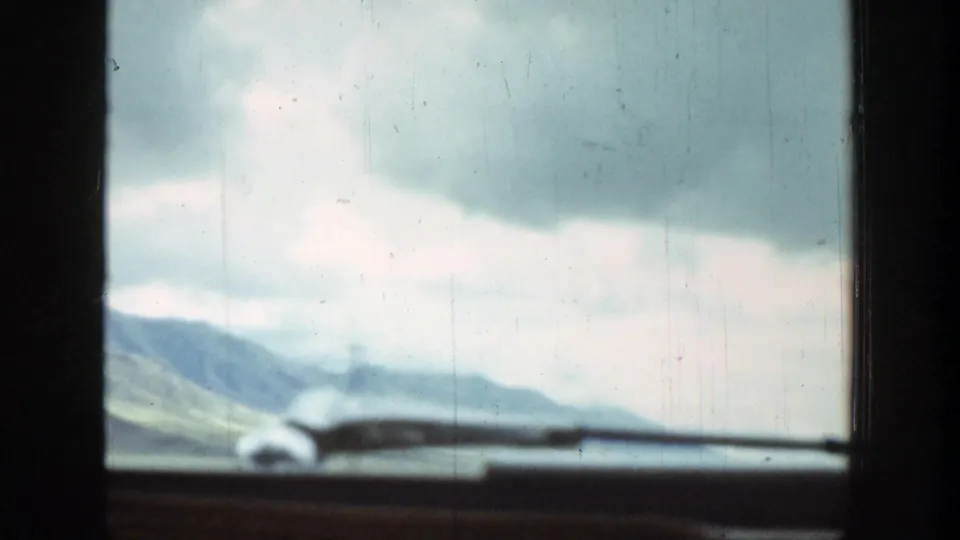 Wyoming 1939 home-movie frame showing fields and mountains through a dark car window, with soft focus and visible film wear.