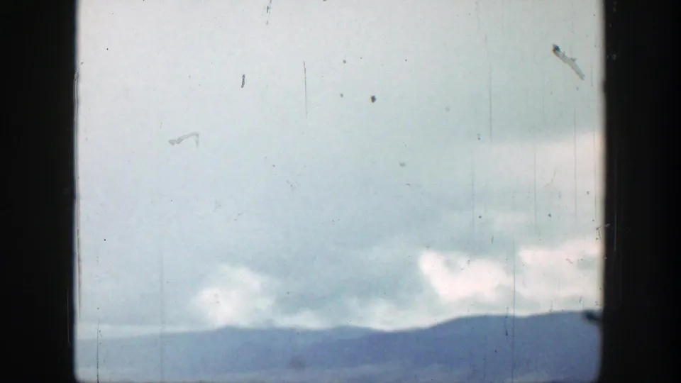 Clouds over a blue mountain ridge in Wyoming, partially obscured by dark vertical framing from the shooting position.