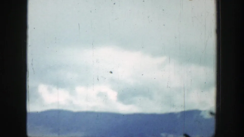 A softer 1939 travel-film view of clouds and a distant Wyoming mountain ridge, with visible dust and vertical film wear.